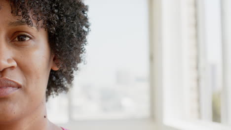 Una-Mujer-Birracial-Con-Pelo-Rizado-Sonríe-Cerca-De-La-Ventana