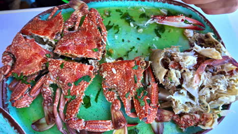 person cracking open fresh crab at an outdoor dining table, showcasing seafood cuisine