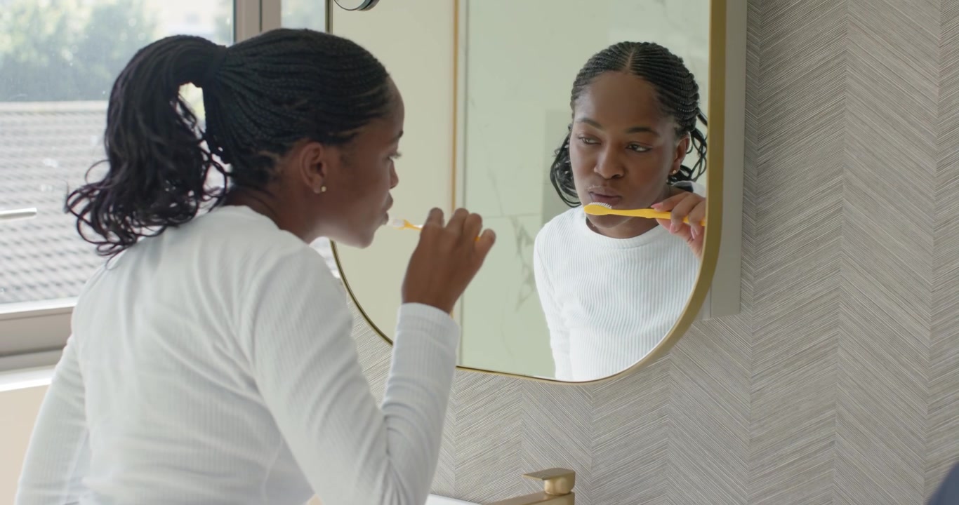 African American woman checking mouth, turning tap and brushing with yellow toothbrush for hygiene