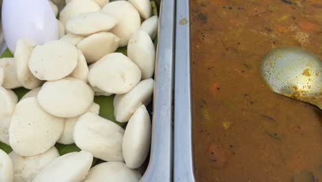 Primer-Plano-De-Sabrosos-Idli-Y-Sambhar-Mantenidos-Uno-Al-Lado-Del-Otro-En-Un-Puesto-Del-Sur-De-La-India-En-Kolkata,-India