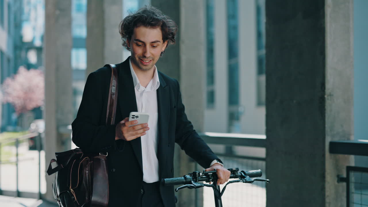 Ung forretningsmand med el-løbehjul bruger smartphone i byen.
