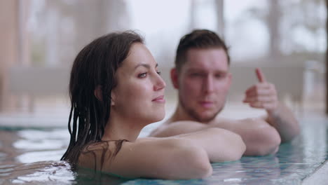 adult man and woman are resting in modern wellness center bathing in swimming pool