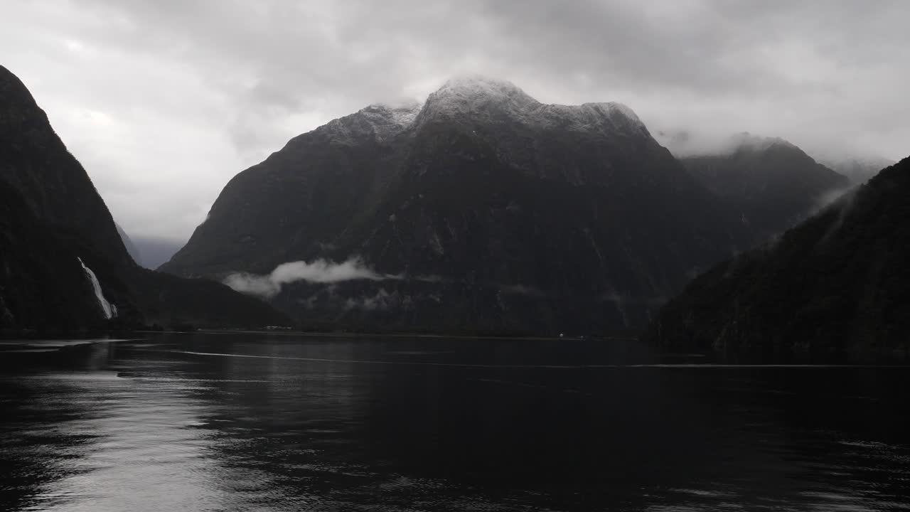 Cliffs and waterfalls at Milford Sound (Piopiotahi), Fiordland National Park on the South Island of New Zealand. Milford Sound surrounded by looming mountains and impressive sheer rock faces.