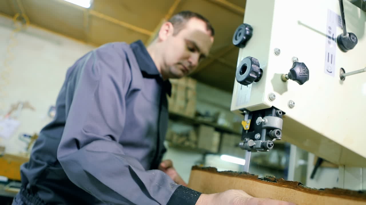 Man Uses An Electric Saw To Cut Wooden Planks. Carpenter is sawing a wooden plank with jig saw machine in carpentry workshop