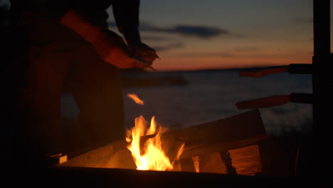 Mann,-Der-In-Der-Abenddämmerung-Campingfeuer-Am-Meer-Anzündet