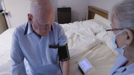 nurse checking elderly man's blood pressure