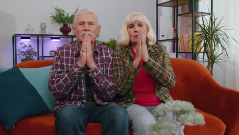 senior elderly family couple grandparents man woman pray with hope, making wish, begging apology