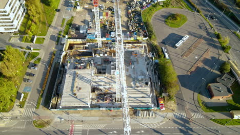 articulated bus and vehicles driving along the city road with tower cranes on a construction site in gdynia, poland