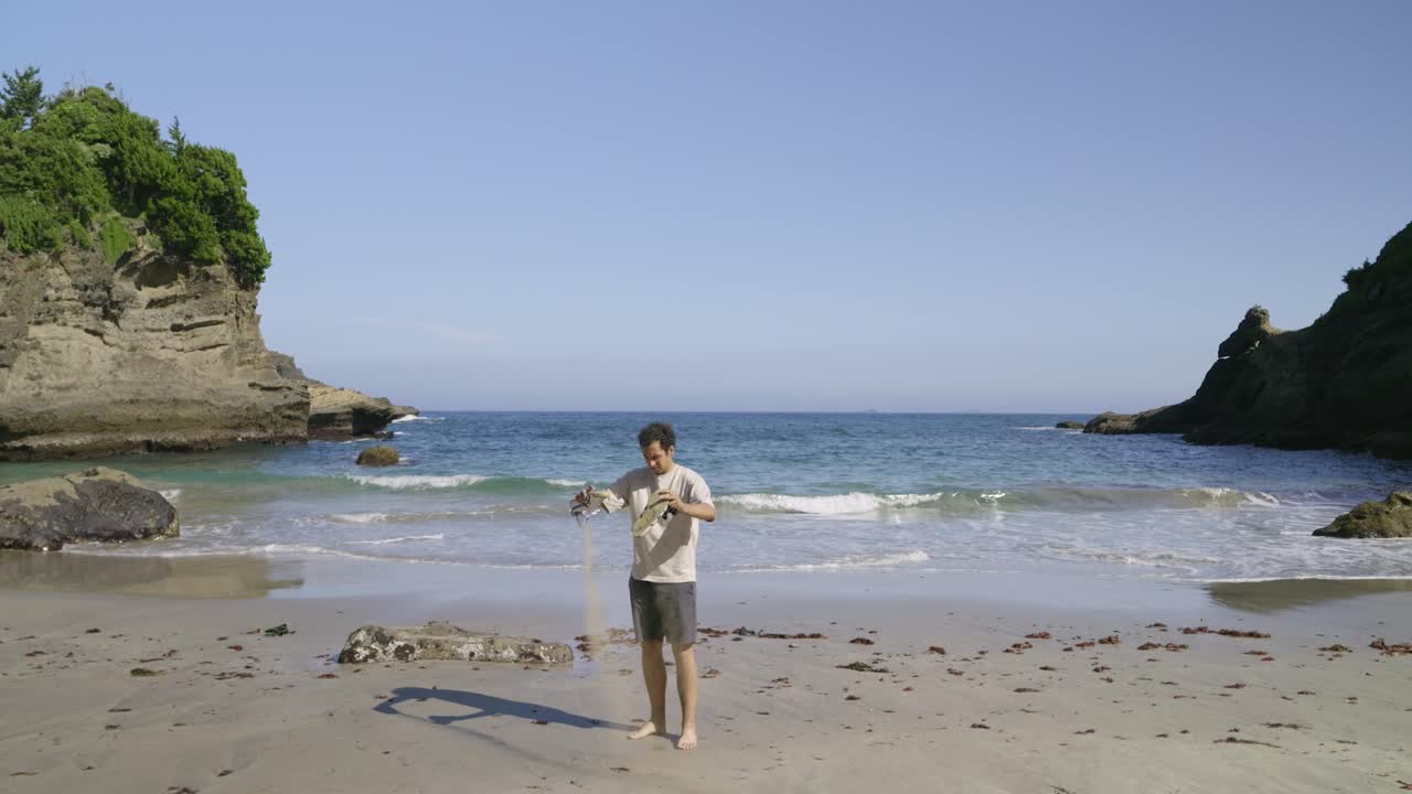 Funny young male clearing sand from shoes at sandy beach