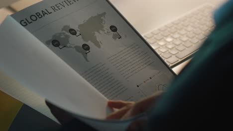 close up businessman hands paging documents reading information on project report working late in office at night