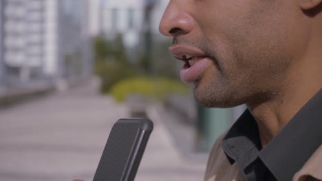 hombre afroamericano usando dictáfono en un teléfono inteligente