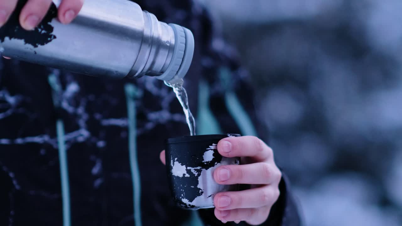 보온병은 추운 겨울 풍경 한가운데 머그잔에 차를 따른다