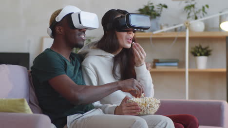 joyous couple watching movie with vr headsets at home