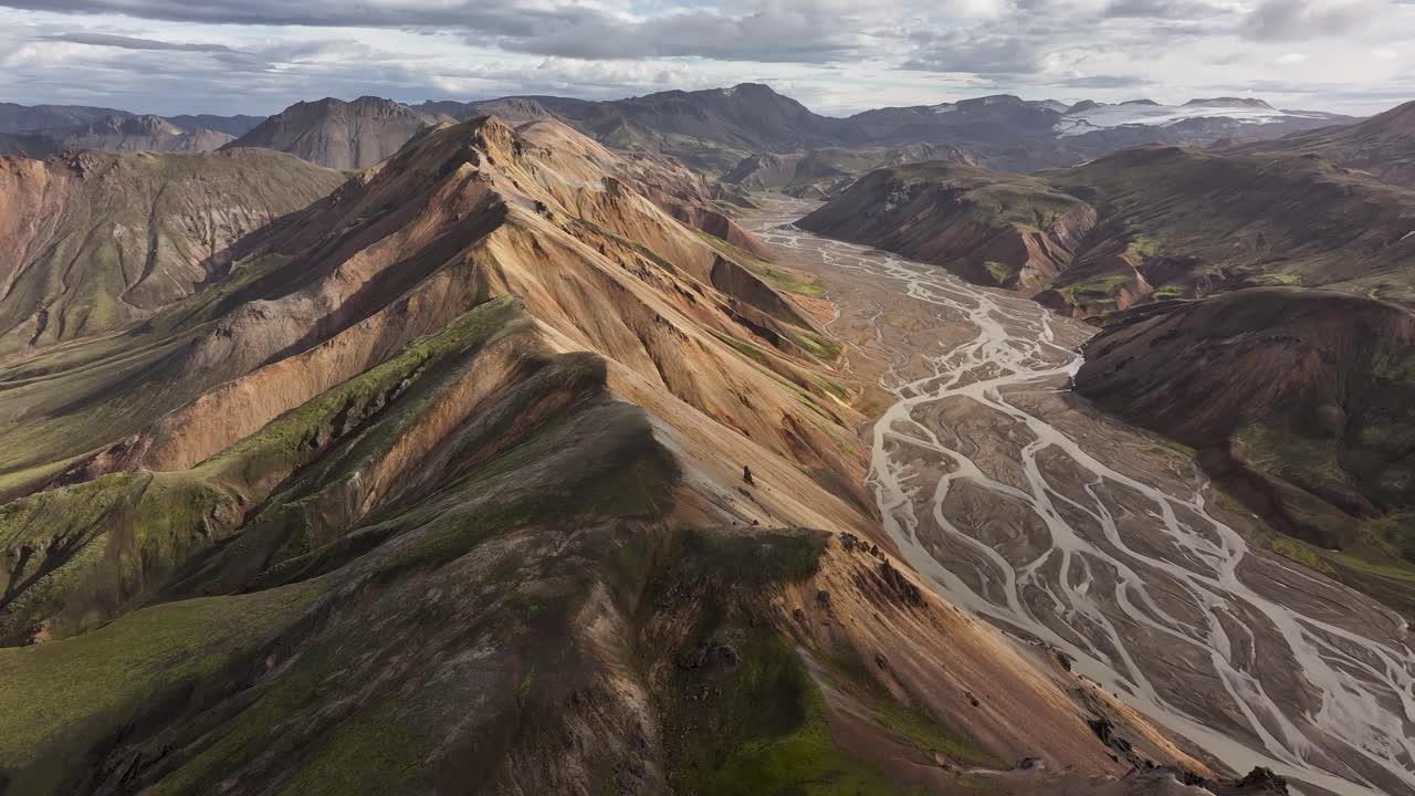 An aerial shot looking over Landmannalagur mountain in Iceland as the golden sun kisses the volcanic mountain face for a perfect cinematic shot