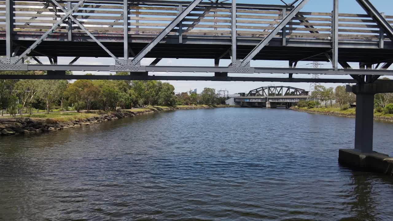Aerial drone flies under bridge over Maribyrnong River in Melbourne