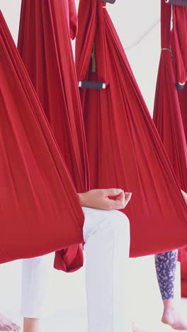 long anti-gravity hammocks hold women group siting and relaxing after advanced workout in gym close view