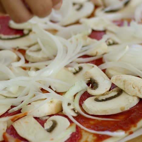 woman placing onion on a homemade pizza