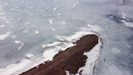 Flying-over-a-sandy-beach-and-beautiful-frozen-lake-on-a-cold-day