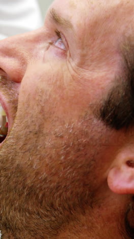 female dentist examining male patient with dental tools