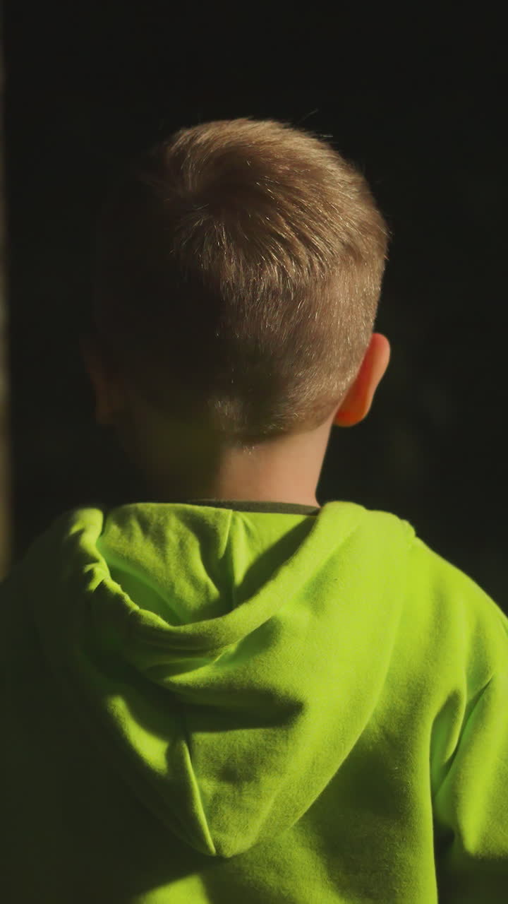 즐거운 어린 소년은 가족과 함께 숲을 걸어 자연에서 주말을 즐기고 편안한 스포츠 의류를 입은 아이가 저녁에 조명 된 덤불에서 놀고 재미있게 놀고 있습니다.