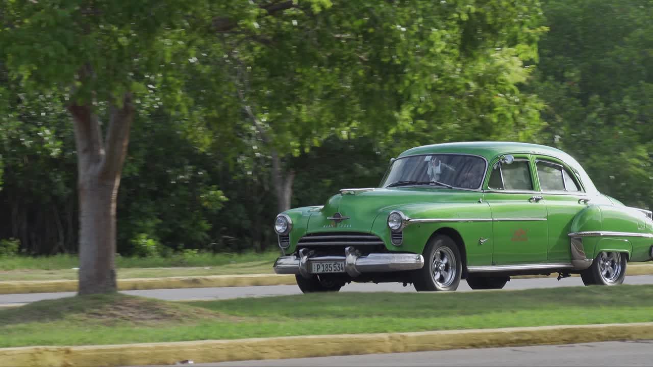 Green Oldsmobile Rocket 88 Sedan car in Vardero, Cuba driving, panning shot