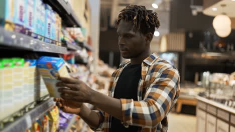 stylish african american guy chooses products in the grocery store