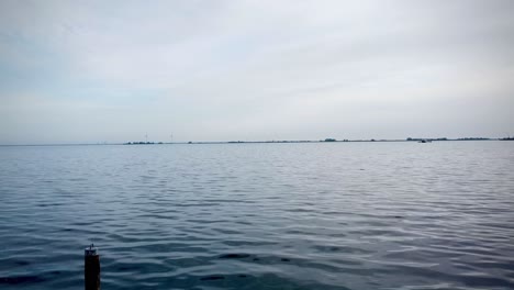 Ein-Malerischer-Blick-Auf-Einen-Fluss,-Der-Unter-Einem-Bewölkten-Himmel-Gegen-Ein-Grünes-Ufer-Fließt