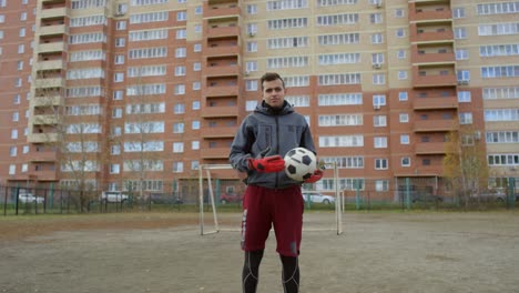 confident male soccer player with ball looking at camera on the field