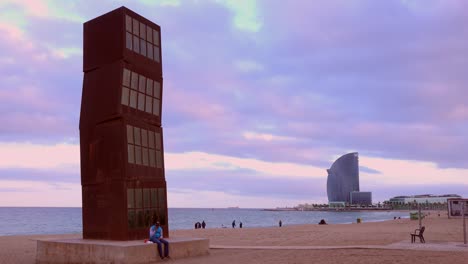 an odd sculpture stands on a beach in barcelona spain