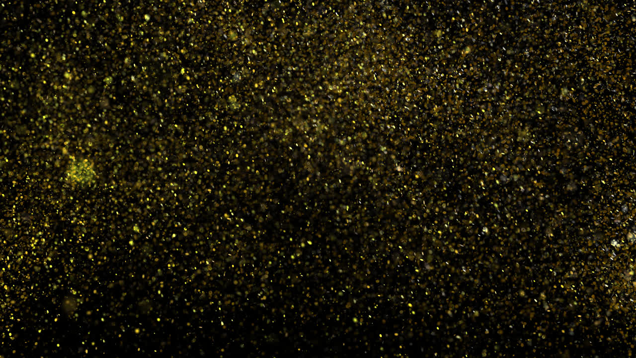 Particelle di glitter dorato che esplodono e brillano su sfondo nero