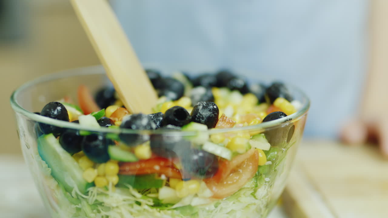 la ensalada de verduras se revuelve en un recipiente de vidrio