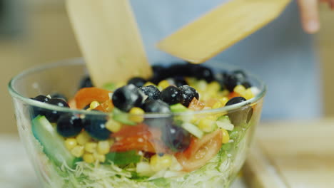 la ensalada de verduras se revuelve en un recipiente de vidrio