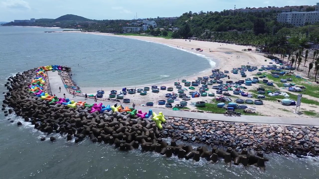 Vista aérea de drone de barcos de pesca tradicionais "thung chai" azuis na praia de Mui Ne, ao lado de quebra-ondas coloridos em forma de X. Cena costeira vibrante e marcante com o mar na província de Binh Thuan, Vietnã.