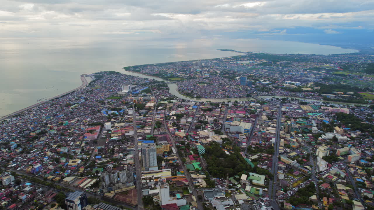 área urbana densa en el sudeste asiático ciudad con río que desemboca en el océano durante la puesta de sol nublada