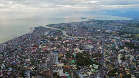 Dense-Urban-Area-In-South-East-Asia-City-With-River-Running-Into-Ocean-During-Cloudy-Sunset