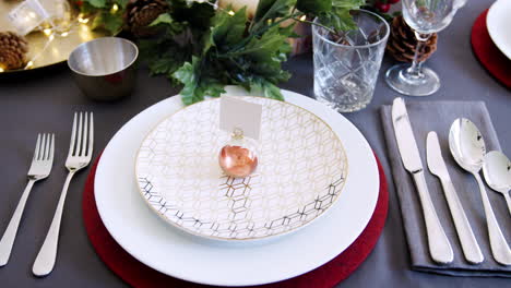 decoración de mesa de navidad con soporte de tarjeta de nombre de bauble dispuesto en un plato y decoraciones de mesa verdes y rojas, detalle, enfoque del estante, vista elevada