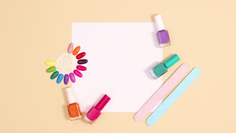 herramientas de manicura y esmalte de uñas se mueven alrededor de la nota de tarjeta de papel en fondo beige. detener el movimiento