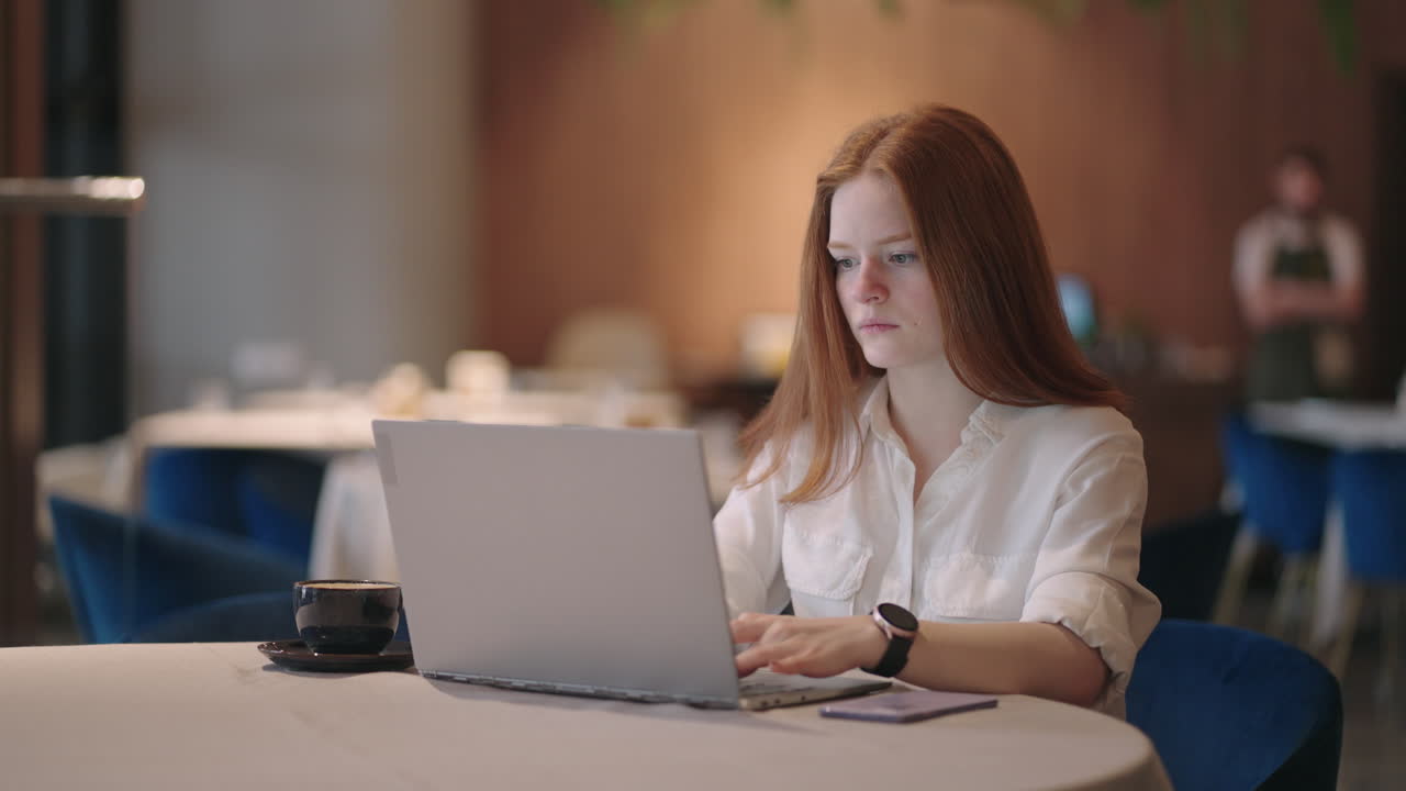 Pretty student woman using laptop in outdoors cafe while having cup of coffee. Cheerful woman working at cafe on laptop. Businesswoman working during layover at modern airport.