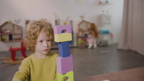 blond little boy playing with foam building blocks in a montessori school 1