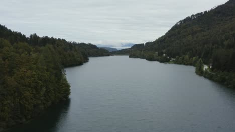 wide view of freibach reservoir at south austrian alps on an overcast day, aerial flyover shot