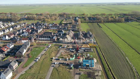 flying towards construction site in a newly built suburban neighborhood surrounded by green meadows