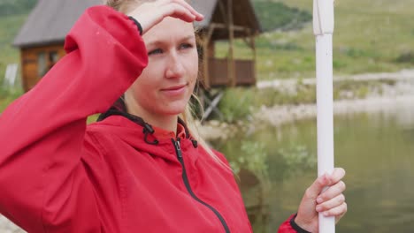 caucasian woman having a good time on a trip to the mountains, holding a paddle, admiring the view