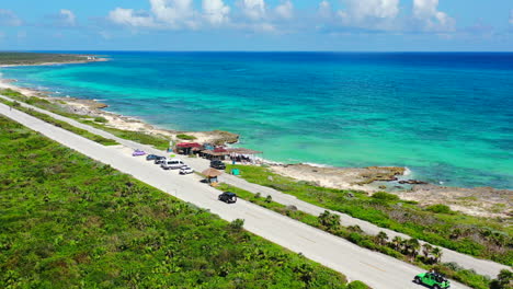 cars driving on coastline of cozumel mexico with turquoise water and white sand beaches on summer day, aerial