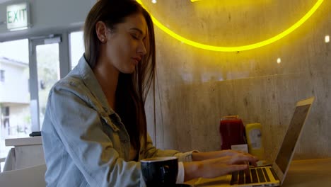 Woman-using-laptop-in-cafeteria-4k