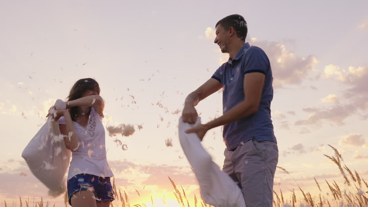 los jóvenes se divierten locamente una mujer golpea su almohada con un amigo las plumas vuelan fi
