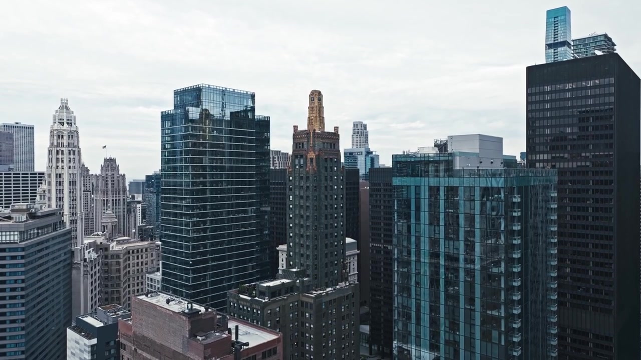 Ascensão aérea para uma torre com topo dourado em Chicago com um cenário de cidade densa