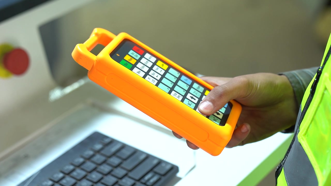 Operador de máquina utilizando un control remoto de computadora para operar una máquina CNC automatizada.