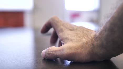 primer plano de la mano masculina golpeando nerviosamente los dedos en la mesa