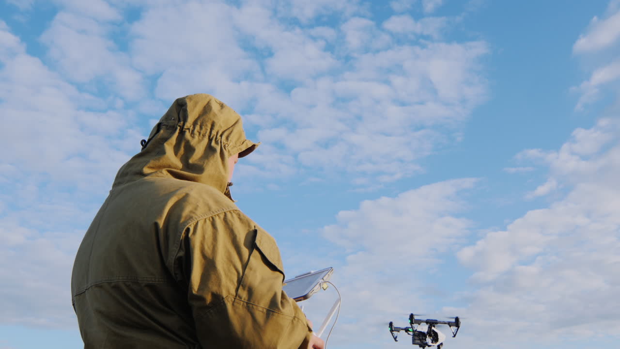 el hombre controla el dron que flota en el aire a su alrededor contra el fondo de sk azul