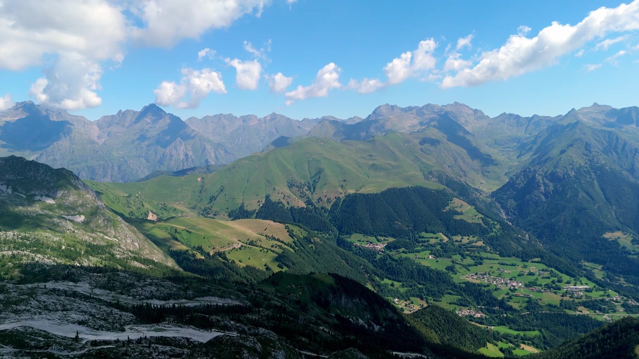 Ripresa aerea con drone ad alta quota che rivela il vasto panorama alpino, i pendii verdi e le cime montuose distanti della Val di Scalve nelle Alpi italiane
